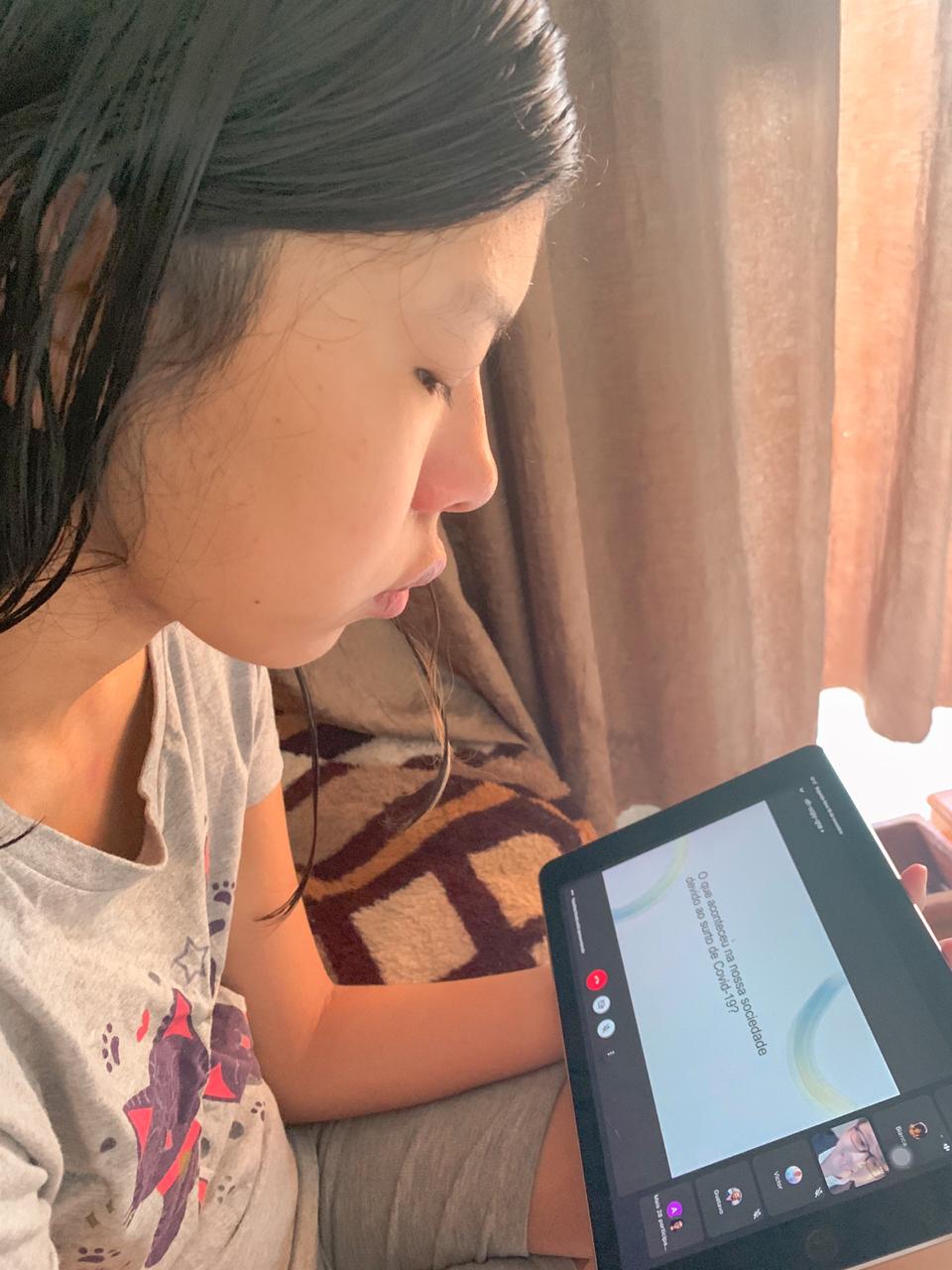 Uma menina assistindo a aula do MONUEM em seu tablet.